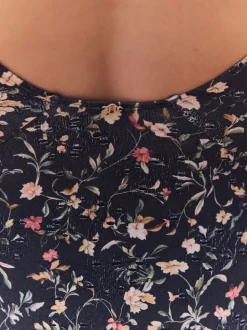 Zwart met broderie en fijne print - Badpak met vormgevende zijrimpeling en buikcorrectie
