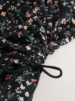 Zwart met broderie en fijne print - Badpak met vormgevende zijrimpeling en buikcorrectie