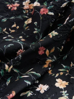 Zwart met broderie en fijne print - Badpak met vormgevende zijrimpeling en buikcorrectie